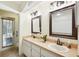 Bright bathroom featuring double sinks, large mirrors, modern lighting fixtures, and a door to the outside at 2990 Longbrooke Way, Clearwater, FL 33760