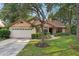 Charming single-Gathering home with a manicured lawn, flower beds, and an attached two-car garage at 2990 Longbrooke Way, Clearwater, FL 33760