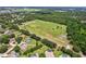Expansive aerial view showcasing a large green sports field bordered by homes, trees, and a walking trail at 3062 Sutton Woods Dr, Plant City, FL 33566