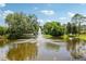 Community lake featuring a fountain with a stone sign for Walden Lake nestled among lush greenery at 3062 Sutton Woods Dr, Plant City, FL 33566
