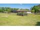 Wide view of the property's lush backyard, accented by a wooden fence, mature trees, and a screened-in lanai at 3452 Forelock Rd, Tarpon Springs, FL 34688