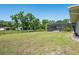 Wide lawn area leading to screened in pool, wooden fence, and other outbuildings at 3452 Forelock Rd, Tarpon Springs, FL 34688