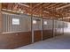 The barn showcases multiple horse stalls with wood panels and steel bars beneath an exposed wood beam ceiling at 3452 Forelock Rd, Tarpon Springs, FL 34688