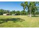 Wide shot of horse property with lush green grass, barns, and mature shade trees under a clear, sunny blue sky at 3452 Forelock Rd, Tarpon Springs, FL 34688