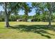 Wide shot of horse property with lush green grass, barns, and mature shade trees under a clear, sunny blue sky at 3452 Forelock Rd, Tarpon Springs, FL 34688