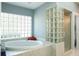Bright bathroom showcasing a luxurious soaking tub next to a glass block shower and window at 3452 Forelock Rd, Tarpon Springs, FL 34688