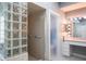 Elegant bathroom featuring a glass block shower wall and modern vanity with Hollywood-style lighting at 3452 Forelock Rd, Tarpon Springs, FL 34688