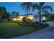 Beautiful home exterior with mature landscaping, lush lawn, and a side-entry two-car garage at twilight at 3452 Forelock Rd, Tarpon Springs, FL 34688