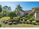 Exterior of tan home featuring meticulous landscaping with bushes and palms at 3452 Forelock Rd, Tarpon Springs, FL 34688