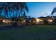 A beautifully lit home at dusk, surrounded by lush landscaping and mature palm trees at 3452 Forelock Rd, Tarpon Springs, FL 34688