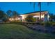 Well-lit home at dusk with manicured landscaping, bushes and a freshly mowed lawn at 3452 Forelock Rd, Tarpon Springs, FL 34688