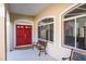 Welcoming front porch with a striking red door, comfortable bench seating, and stylish windows at 3452 Forelock Rd, Tarpon Springs, FL 34688