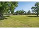 Expansive lawn and home with mature trees, a wooden fence, and an outdoor structure at 3452 Forelock Rd, Tarpon Springs, FL 34688