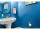 Stylish powder room showcasing a pedestal sink, round mirror, and vibrant blue walls at 533 Vista Ridge Dr, Ruskin, FL 33570