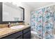 Bathroom with dark vanity, granite counters, a large mirror, and a shower/tub combo with floral curtain at 533 Vista Ridge Dr, Ruskin, FL 33570