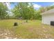 Side view of backyard showcasing the AC unit, mature landscaping, and a large lawn at 5422 Wilkins Trl, Brooksville, FL 34602