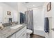 Well-lit bathroom with granite countertop vanity, tiled floors, and shower featuring a stylish patterned shower curtain at 5422 Wilkins Trl, Brooksville, FL 34602