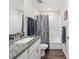 Bright bathroom with gray granite vanity, white cabinets, and shower with decorative curtain at 5422 Wilkins Trl, Brooksville, FL 34602