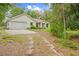 Exterior view of the home showcasing the garage, driveway, and front yard with mature landscaping and trees at 5422 Wilkins Trl, Brooksville, FL 34602