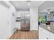 Kitchen area featuring stainless steel refrigerator and white cabinetry in a well-lit room with wood flooring at 5422 Wilkins Trl, Brooksville, FL 34602