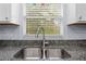 Close up of a granite countertop kitchen sink with stainless steel faucet and window view with closed blinds at 5422 Wilkins Trl, Brooksville, FL 34602