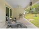 Back patio with fan, seating area and view of the green backyard at 5422 Wilkins Trl, Brooksville, FL 34602