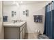 Bright bathroom features double sinks, grey cabinetry, a decorative mirror, and a blue shower curtain at 5687 Barakat Rd, Zephyrhills, FL 33541
