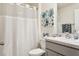 This bathroom offers a shower with a white curtain, flower artwork, and a modern vanity with a single sink at 5687 Barakat Rd, Zephyrhills, FL 33541