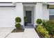 Charming entrance with a gray front door framed by manicured plants and a welcoming walkway at 5687 Barakat Rd, Zephyrhills, FL 33541