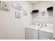A bright laundry room features a white washer and dryer set with decorative signs and storage space at 5687 Barakat Rd, Zephyrhills, FL 33541