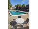A serene, community pool with bright blue water surrounded by plenty of seating and shaded by mature palm trees at 6306 Newtown Cir # 6A3, Tampa, FL 33615