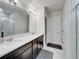 Bathroom with double sink vanity with stone countertop and modern lighting fixtures over a large mirror at 6658 Devlin Ln, Wesley Chapel, FL 33545