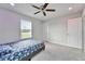 A cozy bedroom featuring a patterned bedspread, a ceiling fan, and a window with blinds at 6658 Devlin Ln, Wesley Chapel, FL 33545