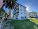 Four-story condo building featuring white facade, balconies, blue roof, and lush green lawn at 800 Bayway Blvd # 14, Clearwater Beach, FL 33767