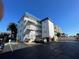 Low angle of a white building with a blue roof showing the staircase and parking area at 800 Bayway Blvd # 14, Clearwater Beach, FL 33767