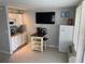 Functional kitchenette with white cabinets, refrigerator, breakfast table and a mounted TV at 800 Bayway Blvd # 14, Clearwater Beach, FL 33767