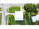 Birds eye view of a gray home with a white roof, green lawn and mature trees at 8502 Grapefruit Ave, Tampa, FL 33619