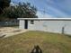 Backyard featuring green grass, trees, concrete patio, and grey exterior of home at 8502 Grapefruit Ave, Tampa, FL 33619