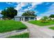 A gray home features a green lawn, mature trees and a long sidewalk leading up to the door at 8502 Grapefruit Ave, Tampa, FL 33619