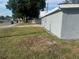 Side yard view of grey home, featuring green grass, nearby trees and neighborhood street at 8502 Grapefruit Ave, Tampa, FL 33619