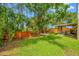 Spacious backyard featuring green grass, wooden fence, mature trees, and screened-in porch at 8514 Manassas Rd, Tampa, FL 33635