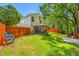 Wide view of the backyard featuring a lush lawn, wooden fence, mature trees, and screened porch at 8514 Manassas Rd, Tampa, FL 33635