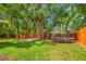A grassy backyard with a basketball court, trampoline, and a wooden fence providing privacy at 8514 Manassas Rd, Tampa, FL 33635