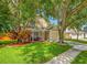 Charming two-story home featuring a manicured lawn, lush trees, and a welcoming front porch with decorative plants at 8514 Manassas Rd, Tampa, FL 33635