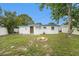 A backyard with green grass, white fencing, a fire pit, and a shed at 8556 91St Ter, Seminole, FL 33777