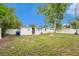 A backyard with green grass, white fencing, a fire pit, a shed, and a large tree at 8556 91St Ter, Seminole, FL 33777