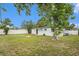 A backyard with green grass, white fencing, a fire pit, a shed, and a large tree at 8556 91St Ter, Seminole, FL 33777