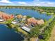 Scenic aerial showcasing colorful townhomes along a tranquil lake with a community pool at 9842 Lake Chase Island Way, Tampa, FL 33626