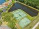 Aerial view of the community amenities, including tennis and basketball courts near a pond and townhome residences at 9842 Lake Chase Island Way, Tampa, FL 33626