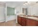 Bathroom featuring double vanity, soaking tub, and tiled floors at 10847 Kirkwall Port Dr, Wimauma, FL 33598